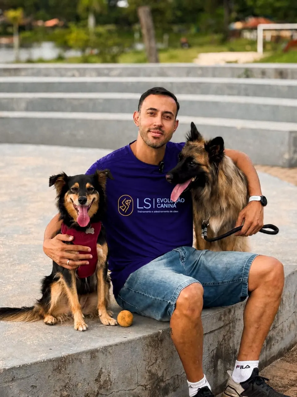 Ricardo, da LS Evolução Canina, sentado com dois cães