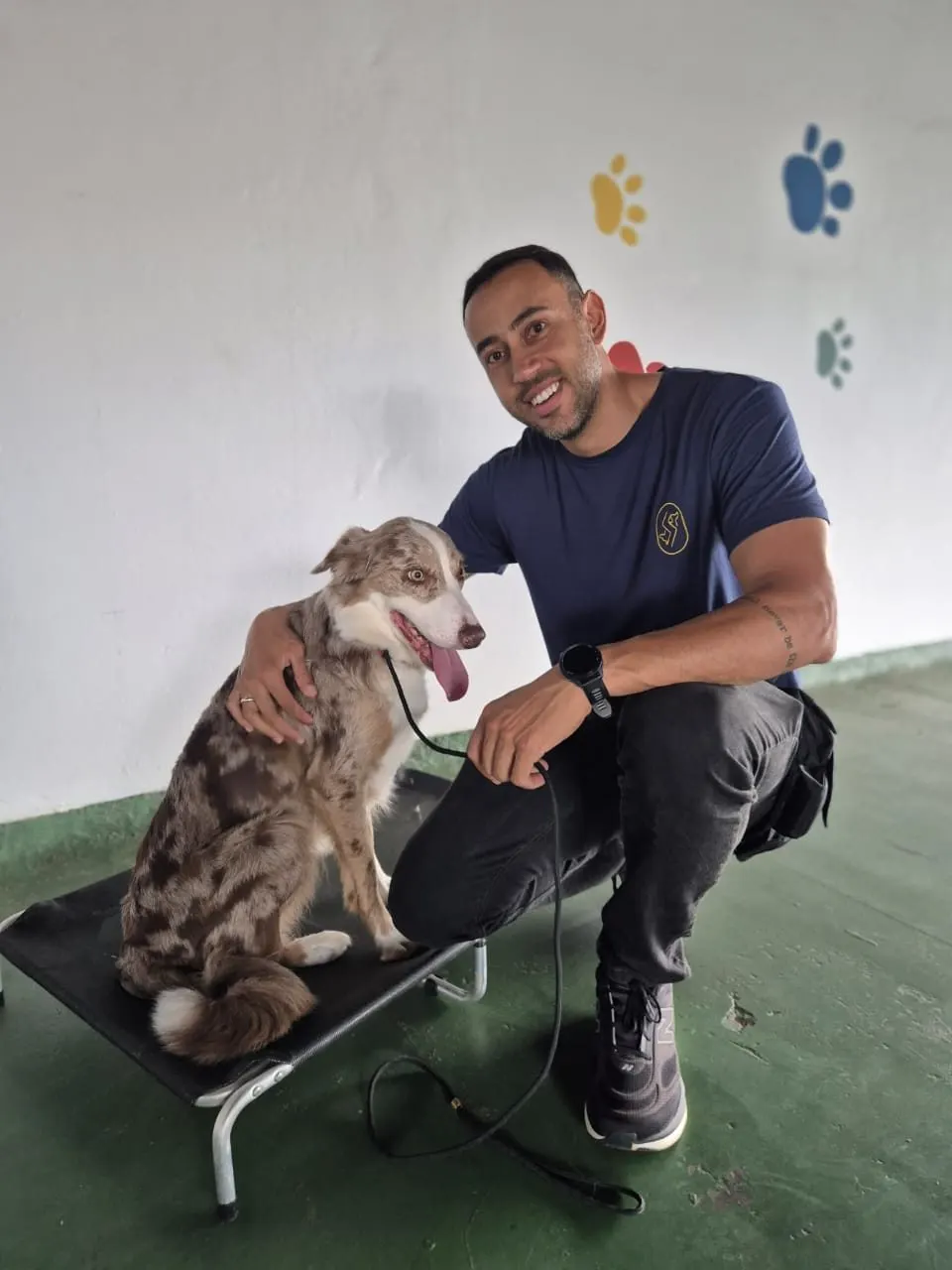 Ricardo sorrindo ao lado de um border collie em cima de uma plataforma